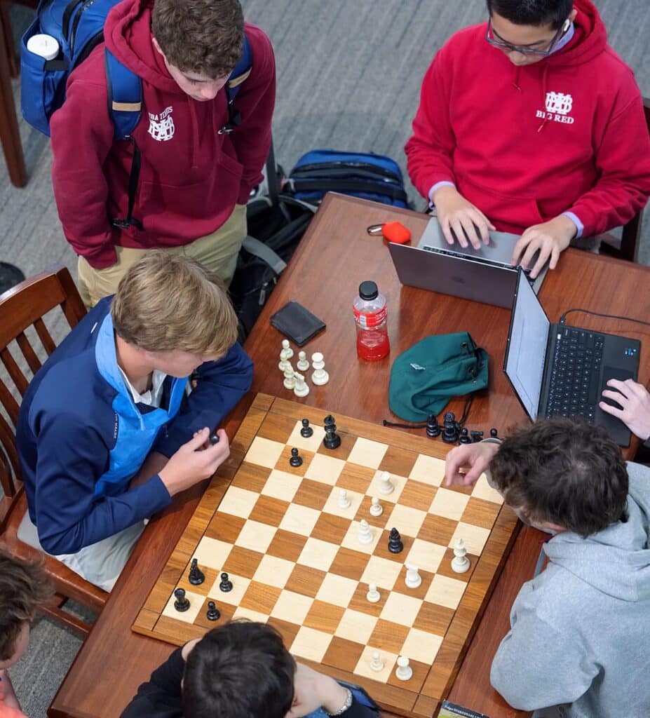 Students playing chess and working on laptops